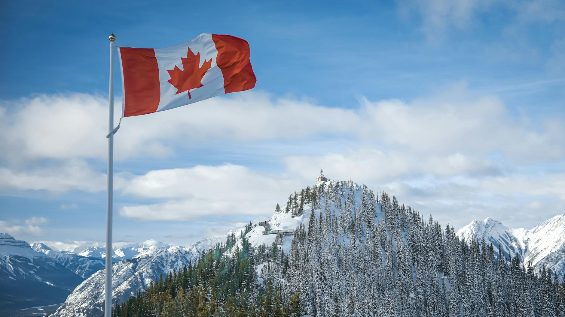 The Canadian flag proudly waving against a backdrop of the majestic snow-covered Rocky Mountains, symbolizing the nation's linguistic diversity and the translation between English and Canadian French.
