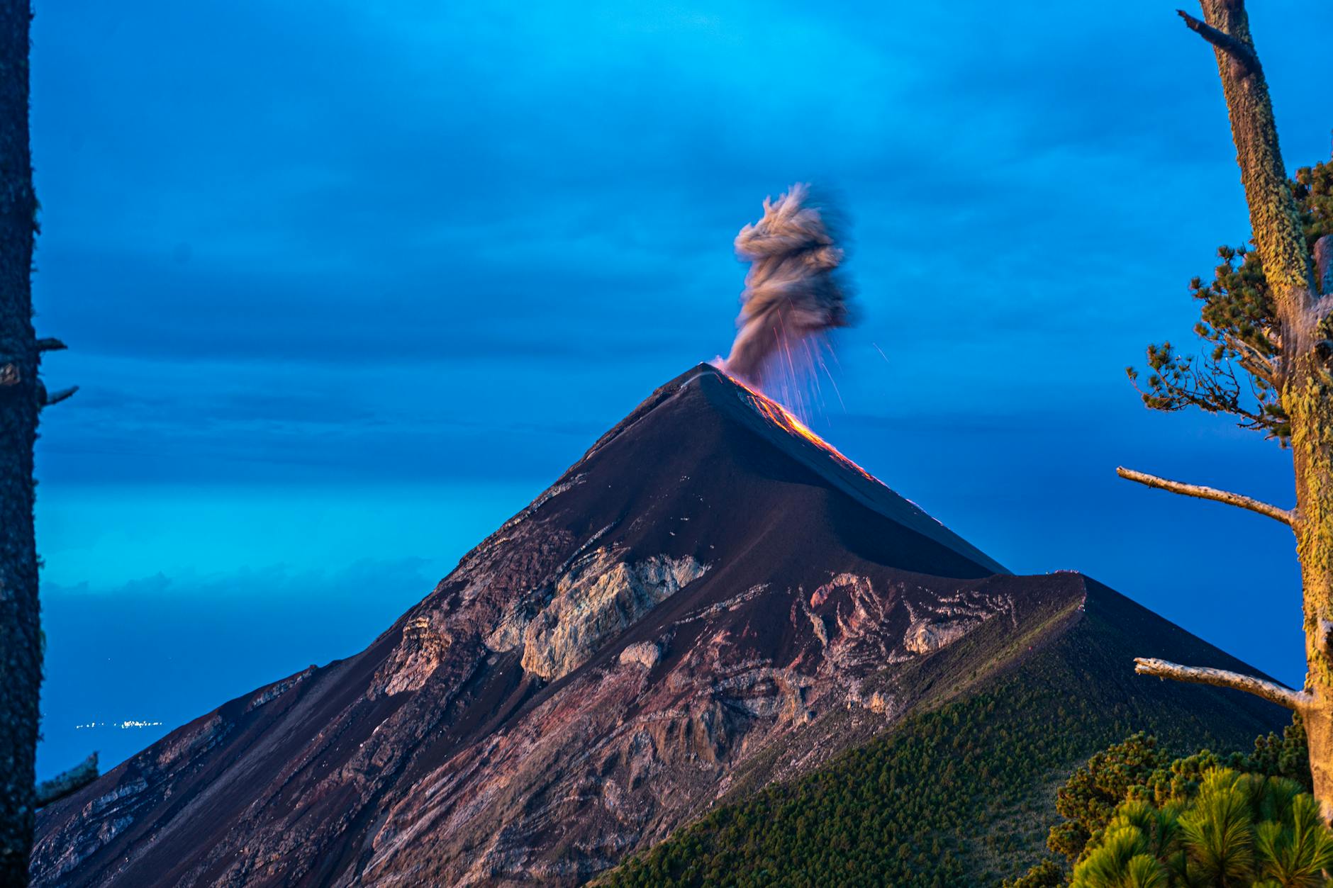 The majestic Fuego Volcano in Guatemala erupts against a twilight sky, embodying the natural splendor and dynamic spirit of the Q'eqchi' Maya homeland.