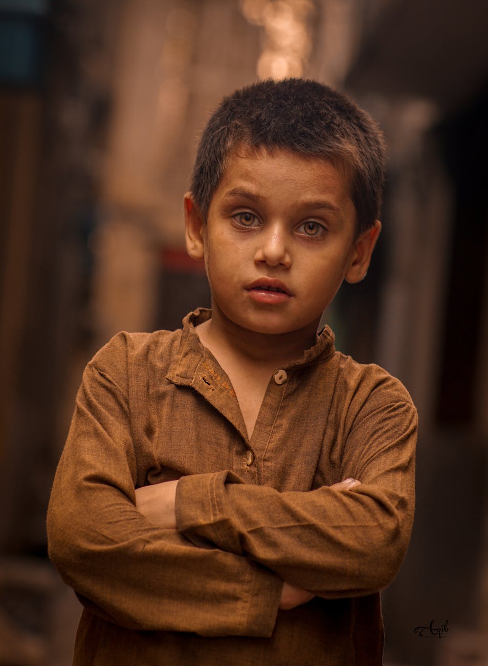 A young boy in traditional attire stands confidently in an alley, his expression reflecting the cultural depth and resilience of the Saraiki-speaking community.