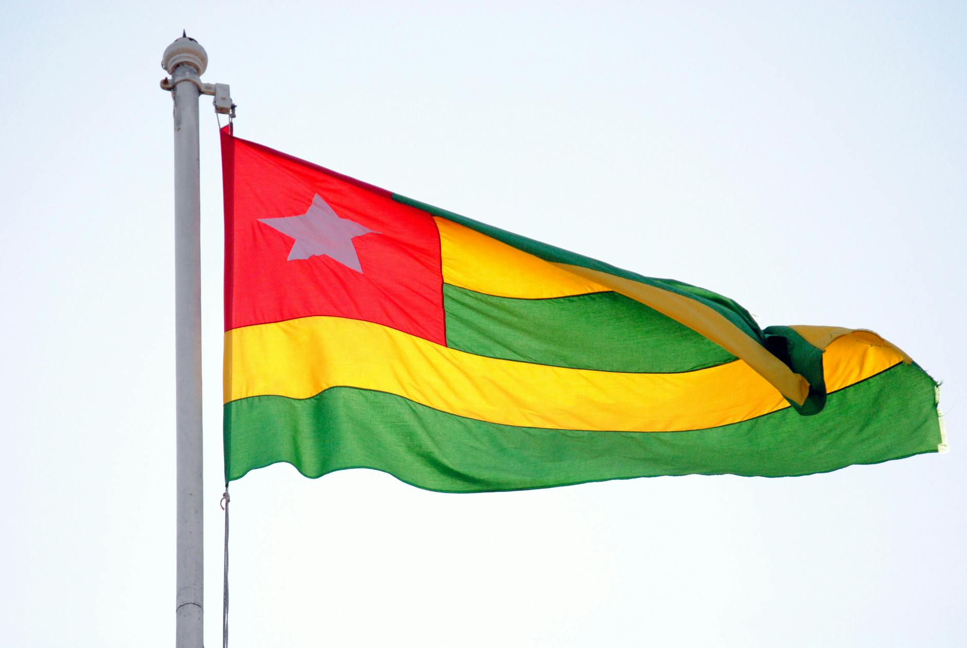 The vibrant national flag of Togo waves against a clear sky, symbolizing the nation's spirit and the cultural richness of the Kabye people.