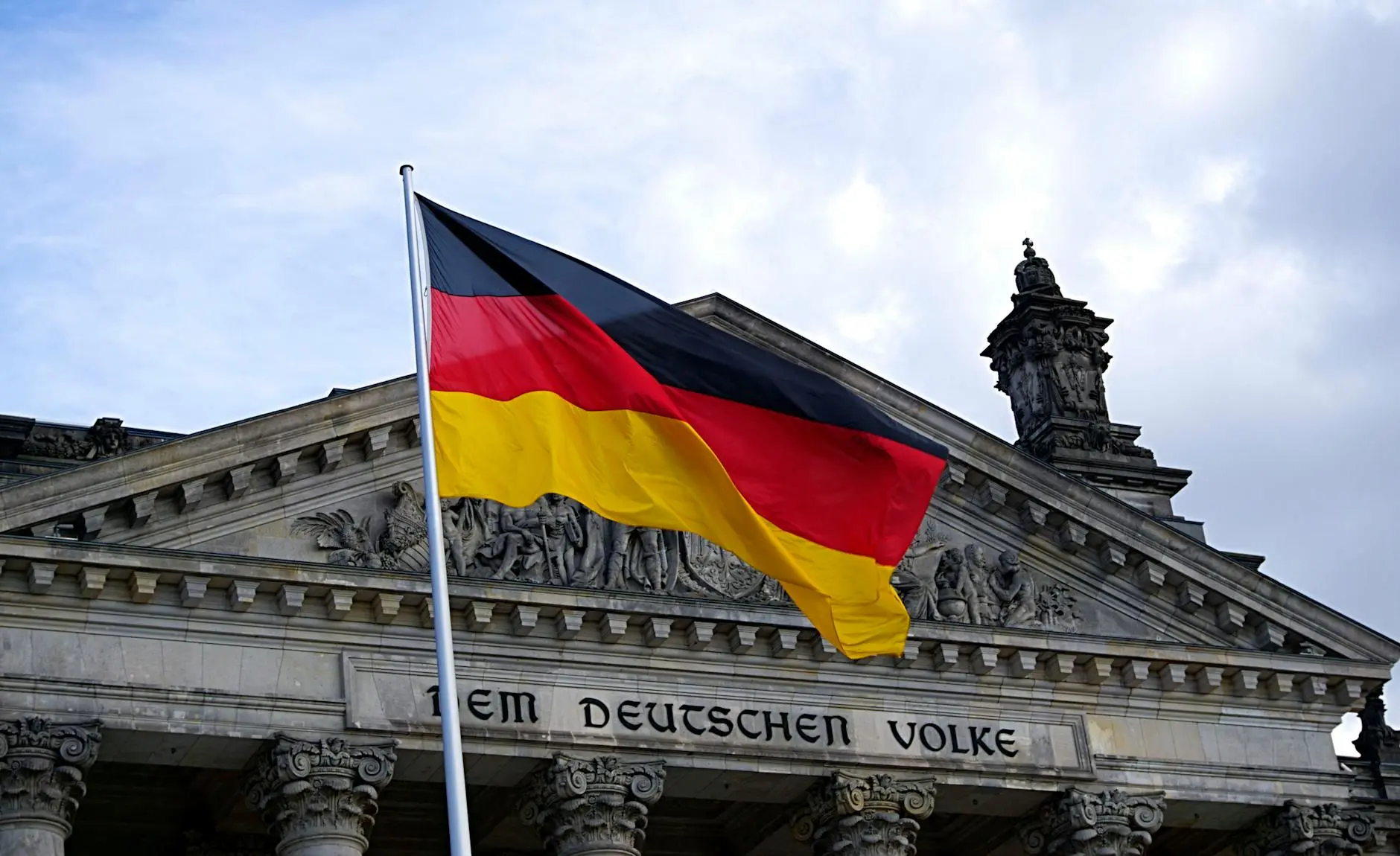 German flag waving in front of building with "Dem Deutschen Volke" meaning "To the German People"