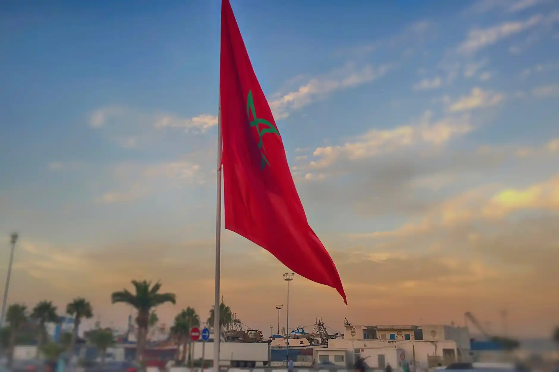 The national flag of Morocco flying at dusk, epitomizing the need for Moroccan Arabic translators in bridging communication gaps for Moroccan communities abroad.