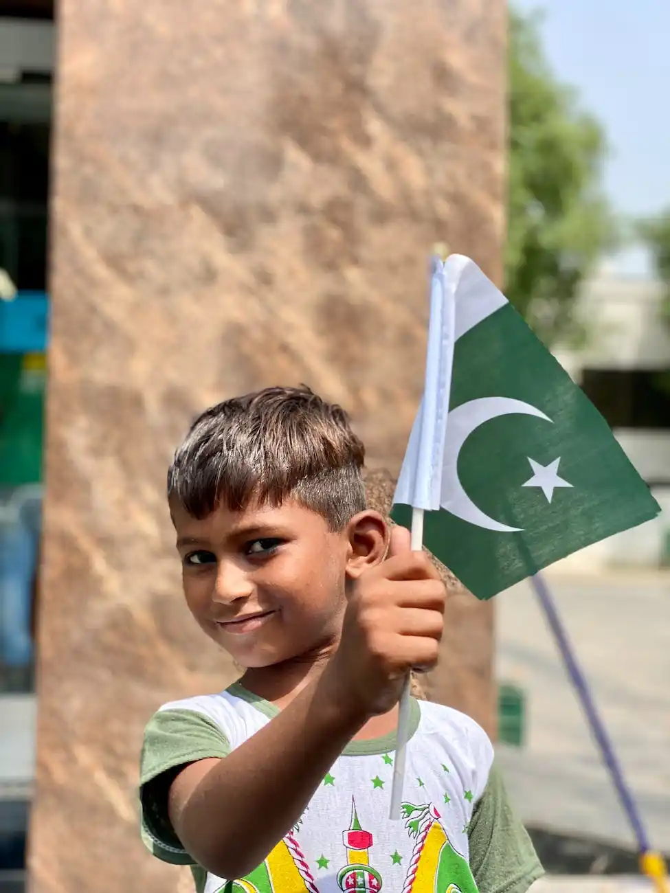 A young boy proudly holding a small Pakistani flag, symbolizing the connection and pride within the Urdu-speaking community.