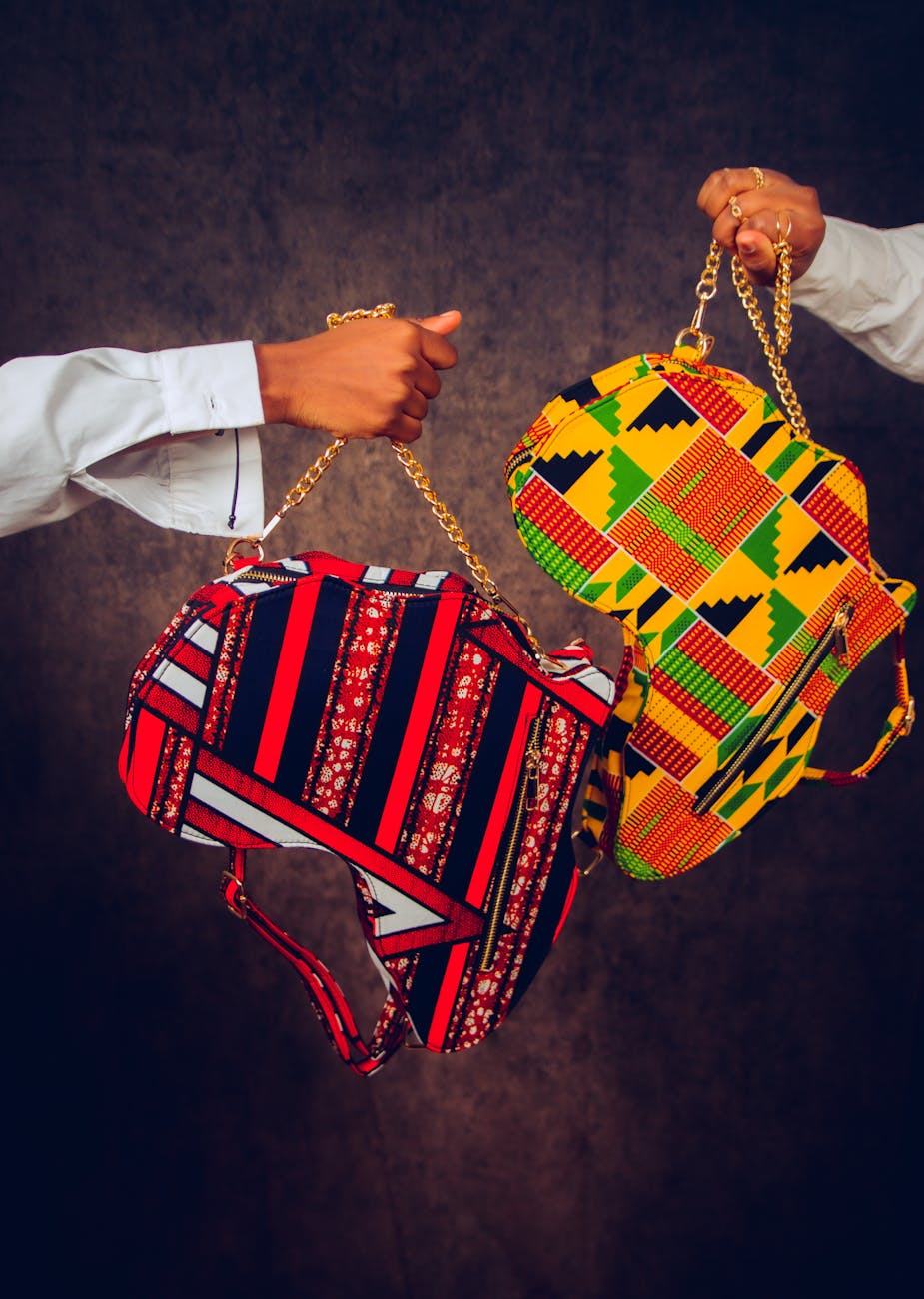Two hands holding vibrant, patterned handbags, reflecting the rich cultural heritage and craft traditions of the Adele-speaking communities in Ghana and Togo.