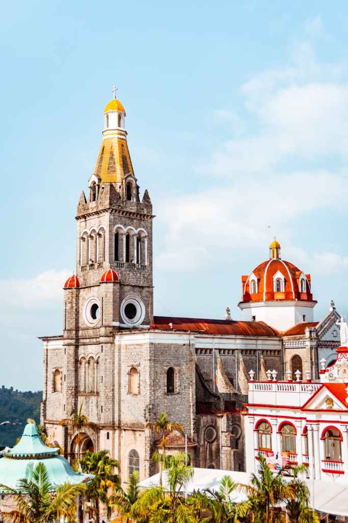 A historic church with a tall bell tower and vibrant red dome, located in a highland region, representing the cultural heritage of the Mixteca region in Mexico where the Mixteco Alto language is spoken.