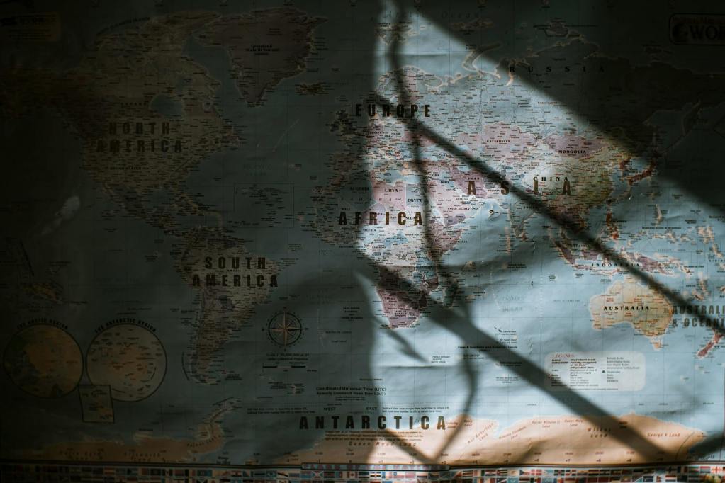 A world map with shadows cast over it, highlighting the diverse regions and cultures, including the Kpelle people of West Africa.